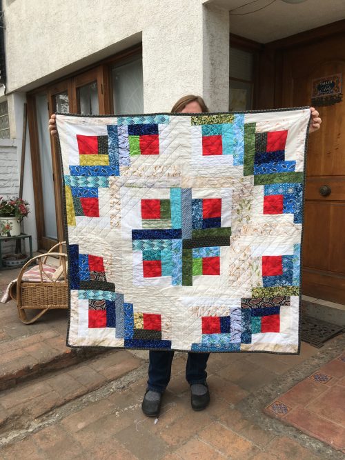 Alison is holding up a square log cabin quilt