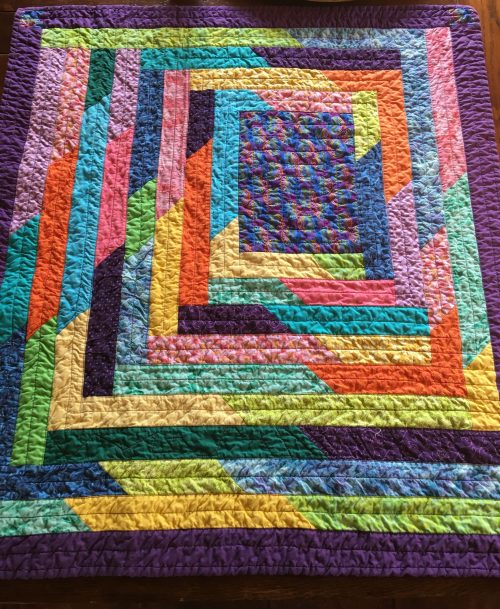A brightly coloured rectangular quilt with an off centre framed effect